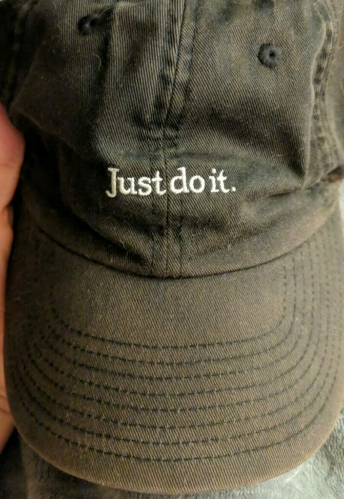 Faded black Nike baseball cap with the words, "Just do it." above the brim.