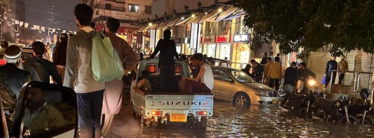 Image of intense flooding on a street in Karachi, prompting the challenging question: "Could you call a place like this home if Jesus asked you to?